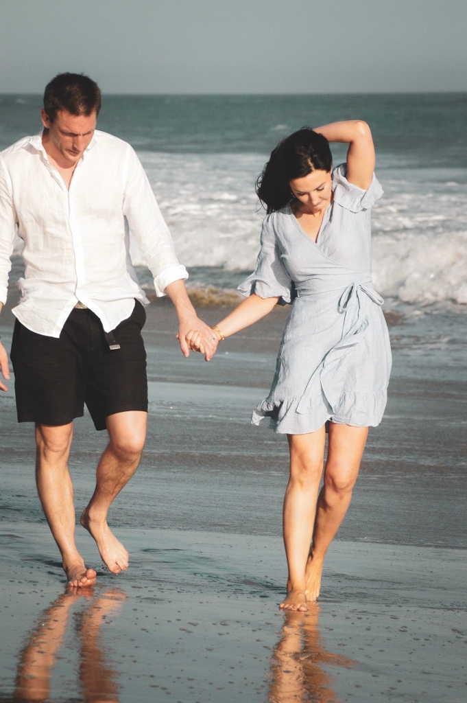 Couple holding hands walking on the beach
